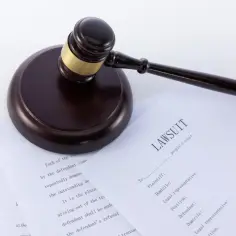 Młotek sędziowski na dokumentach sądowych, w tym na formularzu "LAWSUIT". Może to być wzór wniosku o powołanie świadka.