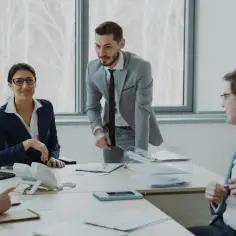 Zespół ludzi w biurze omawia dokumenty przy stole.